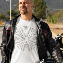 Load image into Gallery viewer, A man wearing a black leather jacket over a white graphic t-shirt and blue jeans stands on a paved road, holding a black motorcycle helmet. A motorcycle is parked in the background with hills and trees behind it.